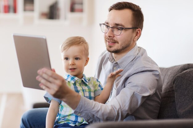 família, infância, paternidade, tecnologia e conceito de pessoas - feliz pai e filho com computador tablet pc jogando ou conversando com vídeo em casa