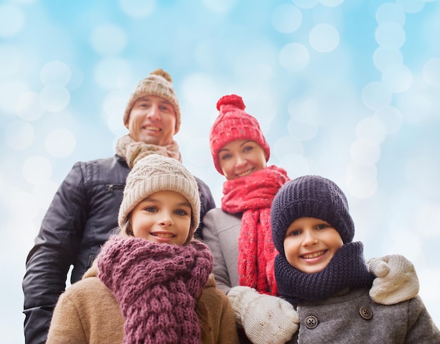 Família, infância, temporada e conceito de pessoas - família feliz em roupas de inverno sobre fundo de luzes azuis