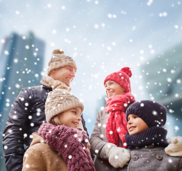 família, infância, temporada e conceito de pessoas - família feliz em roupas de inverno sobre o fundo da cidade nevada