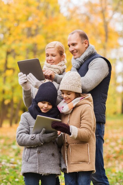 família, infância, temporada, tecnologia e conceito de pessoas - família feliz com computadores tablet pc no parque outono