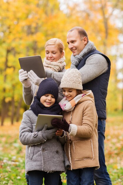 família, infância, temporada, tecnologia e conceito de pessoas - família feliz com computadores tablet pc no parque outono