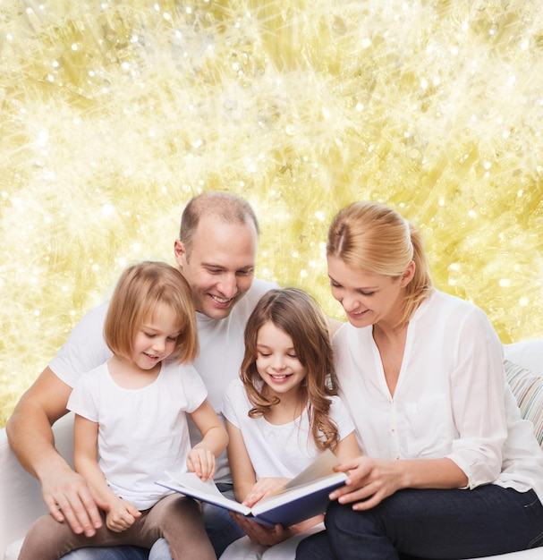 familia, infancia, vacaciones y gente - madre, padre y niñas sonrientes leyendo libros sobre fondo de luces amarillas