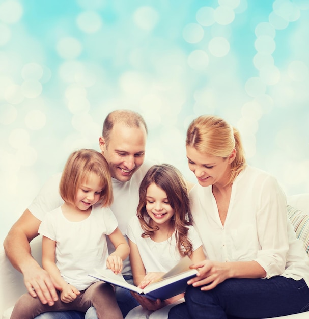 familia, infancia, vacaciones y gente - madre, padre y niñas sonrientes leyendo libros sobre fondo de luces azules