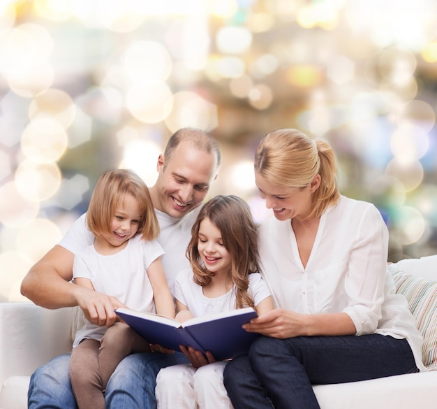 Foto familia, infancia, vacaciones y gente - madre, padre y niñas sonrientes leyendo libros sobre fondo de luces