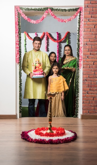 Família inteligente indiana asiática dando as boas-vindas a lakshmi ou laxmi idol no festival diwali com pooja thali e doces. parado na porta de entrada