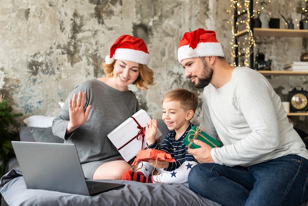 Familia intercambiando regalos mientras videollamadas a familiares en Navidad