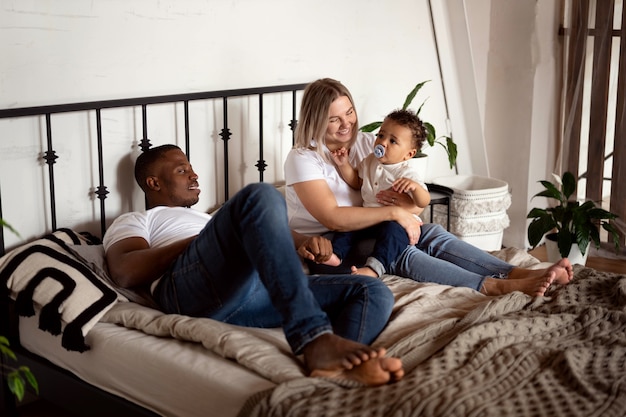 Foto familia internacional acostada en la cama