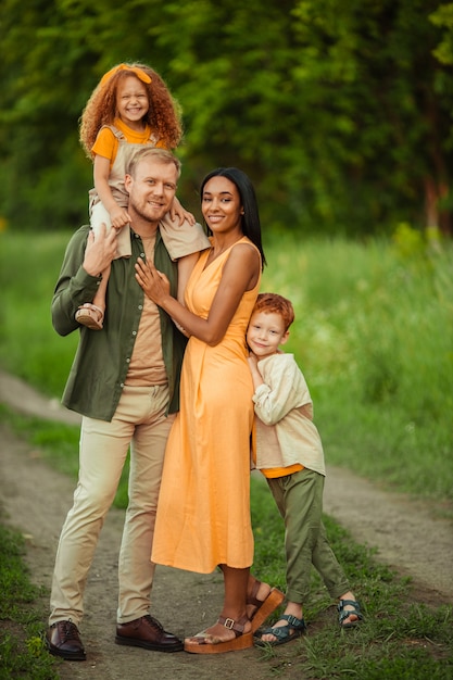 Familia internacional feliz en un paseo de verano en el parque.