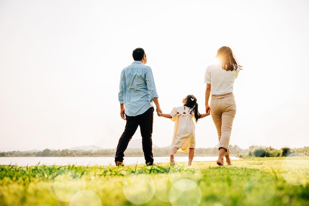 Familia japonesa feliz caminando juntos en un jardín pintoresco con un hermoso telón de fondo natural y el sol brillando disfrutando de tiempo de calidad al aire libre Cuidado familiar vista posterior