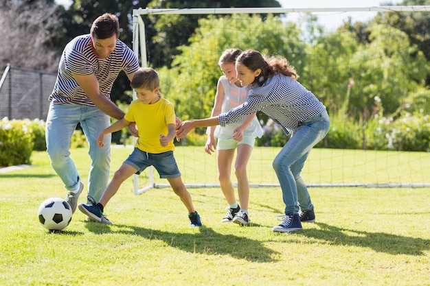 Foto família jogando futebol junta no parque