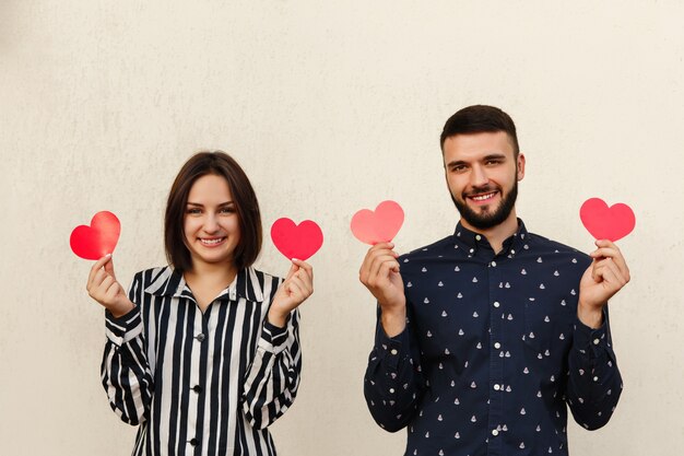 Foto família jovem com dois corações vermelhos, olhando para a câmera.