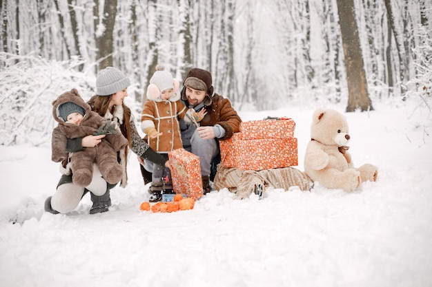 Família jovem com dois filhos na floresta de inverno e posando para uma foto