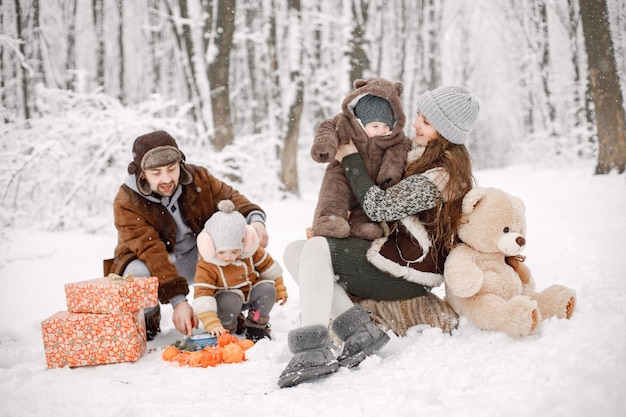 Família jovem com dois filhos na floresta de inverno e posando para uma foto