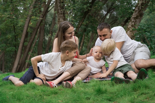 Família jovem com três filhos ao ar livre. Grande e feliz família descansando na natureza