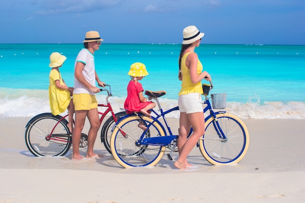 Família jovem, de, quatro, montando, bicycles, ligado, um, tropicais, praia areia