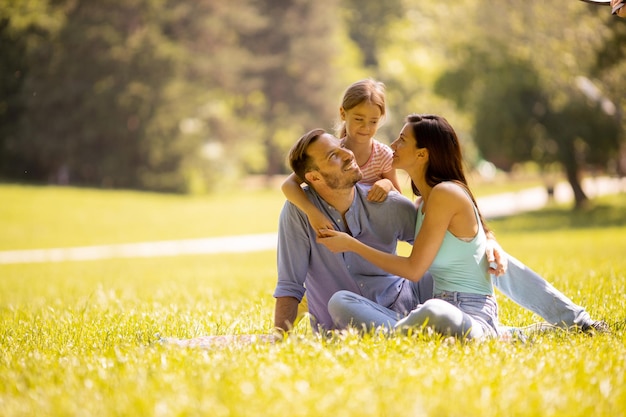 Família jovem e feliz com a filhinha se divertindo no parque em um dia ensolarado