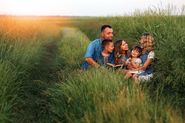 Família jovem e feliz com crianças lendo a Bíblia na natureza