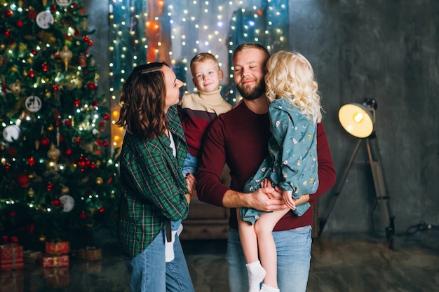 Família jovem e feliz com dois filhos na árvore de Natal