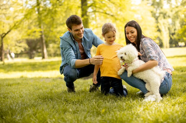 Família jovem e feliz com um lindo cachorro bichon no parque