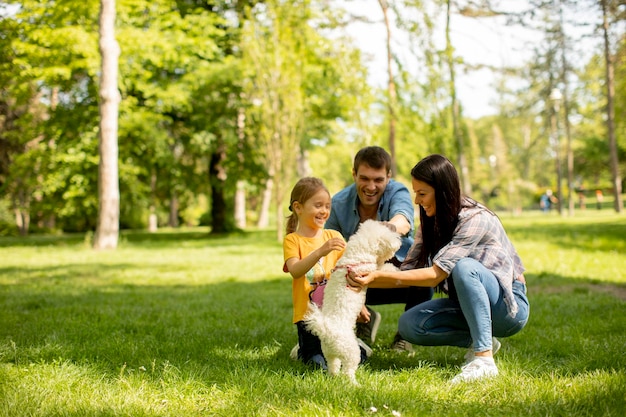 Família jovem e feliz com um lindo cachorro bichon no parque