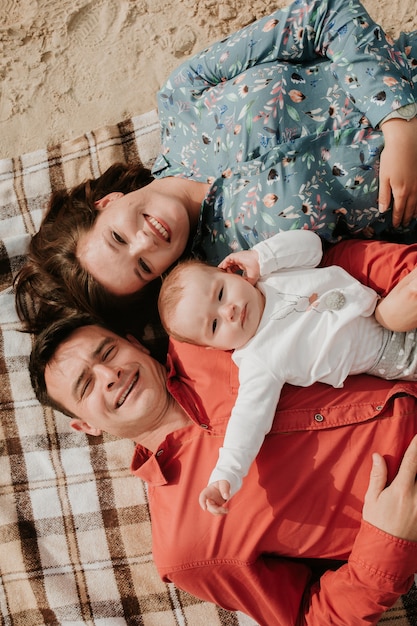 Família jovem e feliz deitada na praia