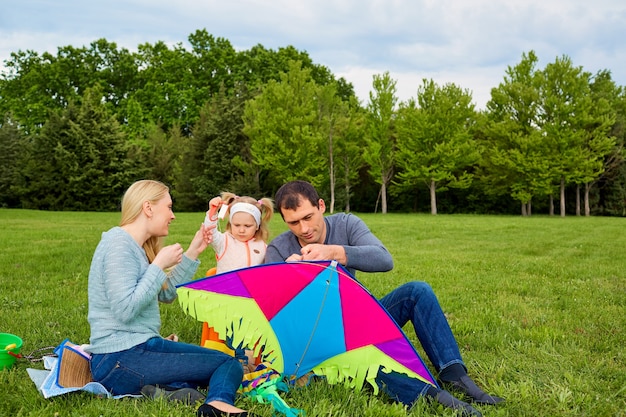 Família jovem e feliz empinando uma pipa no parque