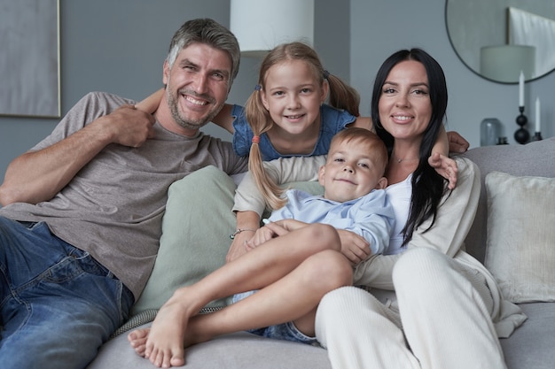 Família jovem e feliz relaxando e se divertindo em uma casa moderna indooor