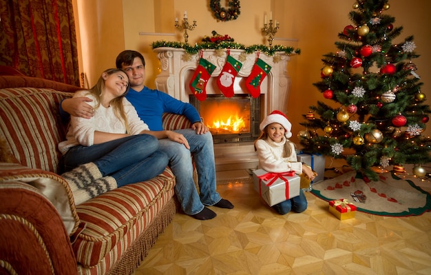 Família jovem e feliz relaxando perto da lareira no Natal