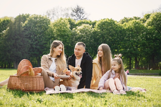 Família jovem e seu cachorro corgi fazendo piquenique em um parque