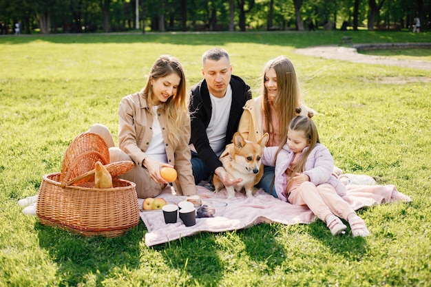 Família jovem e seu cachorro corgi fazendo piquenique em um parque