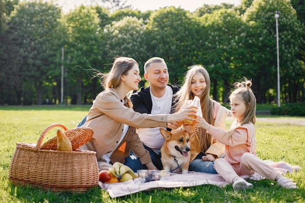 Família jovem e seu cachorro corgi fazendo piquenique em um parque