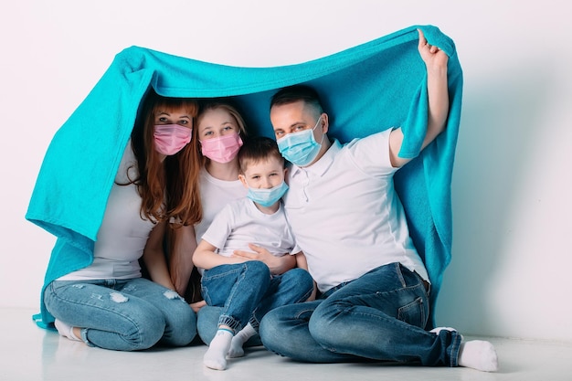 Foto família jovem em máscaras médicas durante a quarentena em casa.