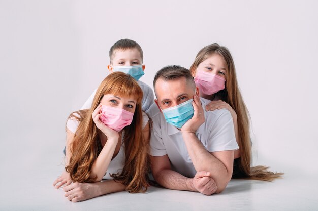 Foto família jovem em máscaras médicas durante a quarentena em casa.