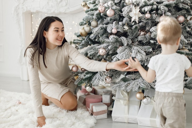 Família jovem em roupas brancas decorando a árvore de Natal em casa