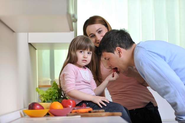 família jovem feliz almoça com frutas frescas e alimentos vegetais na cozinha brilhante