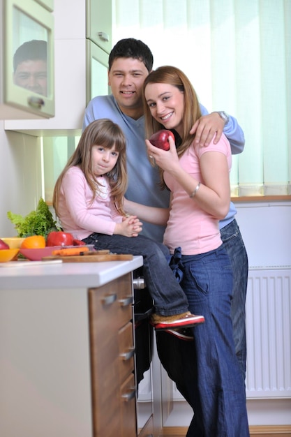 família jovem feliz almoça com frutas frescas e alimentos vegetais na cozinha brilhante