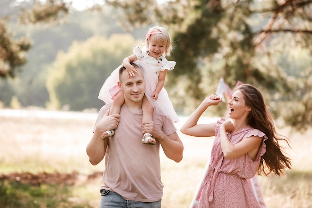 Família jovem feliz andando no parque de verão