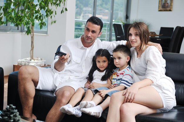 família jovem feliz assistindo tv plana em casa moderna interior