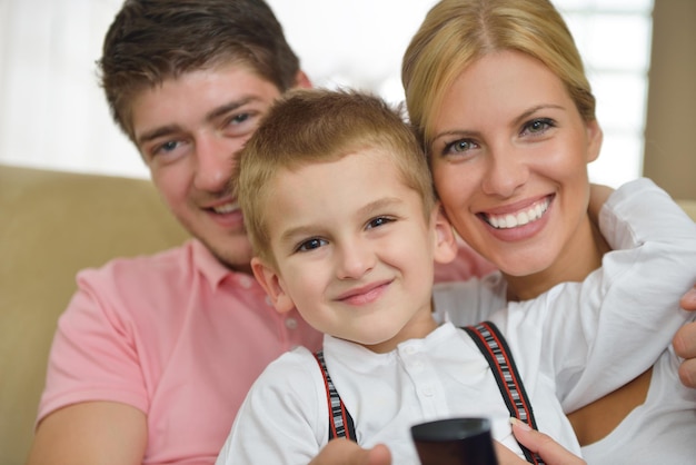 família jovem feliz com crianças na sala de estar moderna e brilhante se divertir e olhar grande tv lcd plana