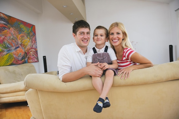 família jovem feliz com crianças na sala de estar moderna e brilhante se divertir e olhar grande tv lcd plana