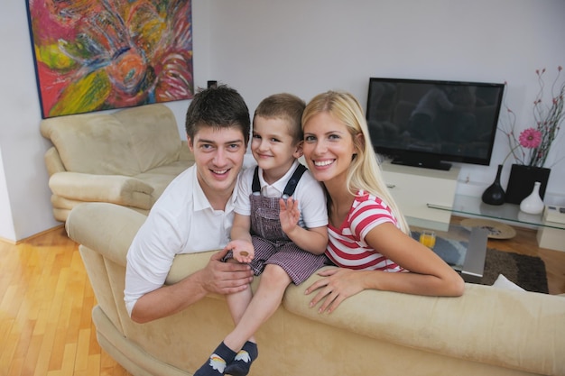 família jovem feliz com crianças na sala de estar moderna e brilhante se divertir e olhar grande tv lcd plana