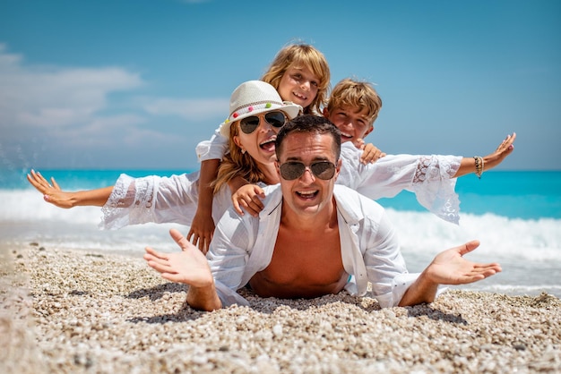 Família jovem feliz com crianças se divertindo na praia.