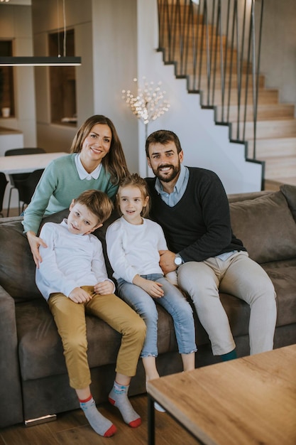 Família jovem feliz com dois filhos aproveita o tempo juntos no sofá na sala de estar