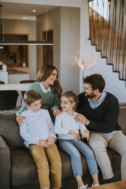 Família jovem feliz com dois filhos aproveita o tempo juntos no sofá na sala de estar