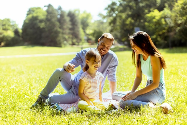 Família jovem feliz com filha bonitinha se divertindo no parque em um dia ensolarado