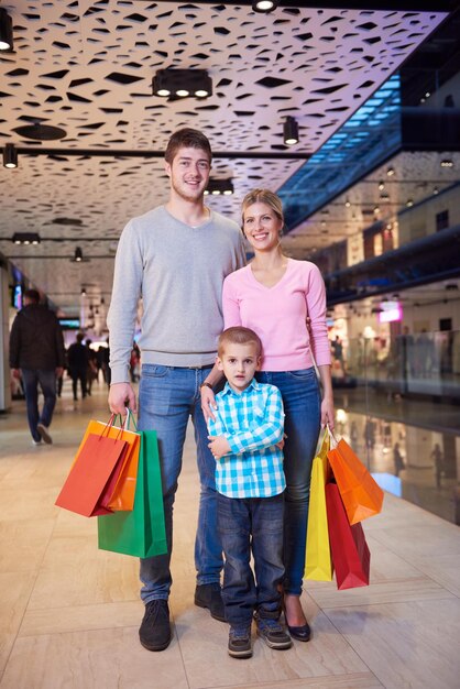 Foto família jovem feliz com sacolas de compras no shopping