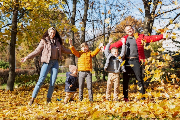 Família jovem feliz com três filhos no parque outono. Amor e ternura. Ande na época dourada.