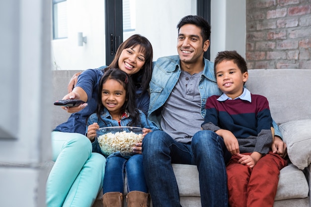 Família jovem feliz comendo pipoca enquanto assistia tv