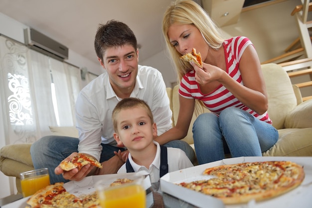 Família jovem feliz comendo pizza saborosa com queijo e suco de laranja fresco e saudável