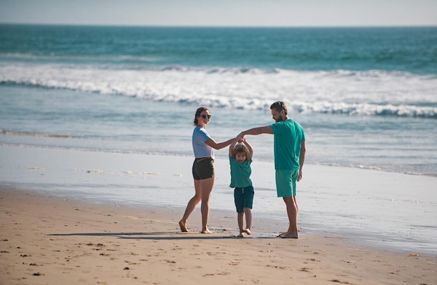 Família jovem feliz corre e salta na praia de verão criança com pais de mãos dadas viagem familiar